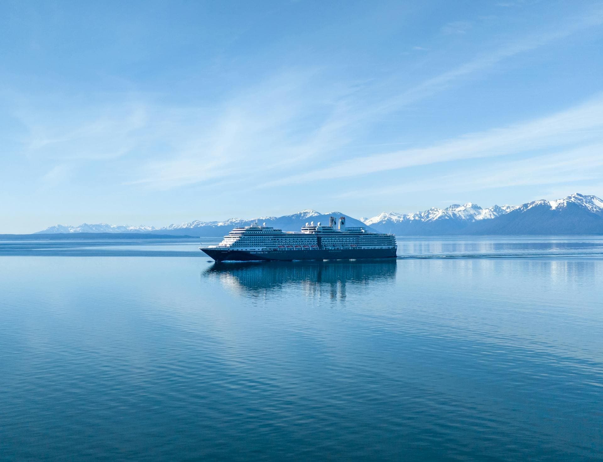 A large cruise ship sailing past a tidewater glacier in southeast Alaska under low cloud